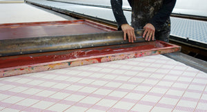 Person working with a large screen printing frame on a table.